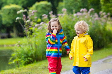 Kids play in rain and puddle in autumn