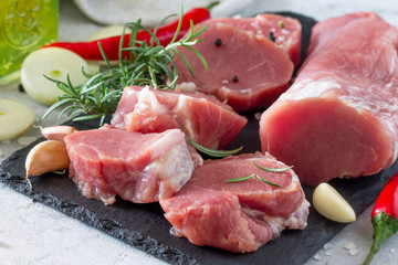 Fresh meat fillets raw with chili, onions, spices and rosemary on a cutting board.