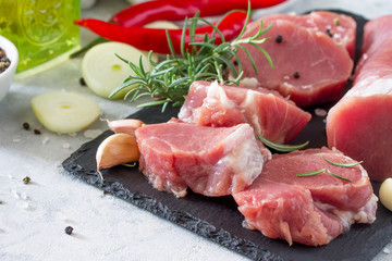 Fresh meat fillets raw with chili, onions, spices and rosemary on a cutting board. Copy space.
