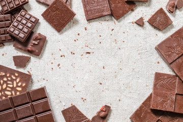 Variety of bars of raw homemade chocolate on cloth background. Vegetarian concept of healthy food. Top view. Copy space