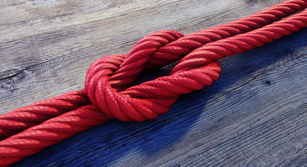 Kreuzknoten mit rotem Seil auf Holz