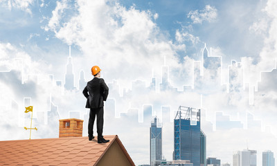 Engineer man standing on roof and looking away. Mixed media