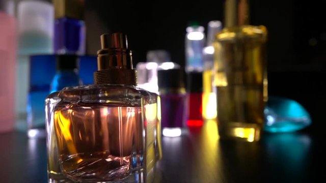 Woman opens small bottle and sprays perfume in the dark. Super slow motion close-up video
