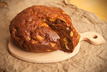 Homemade cocoa cake with fruits in paper on wooden board