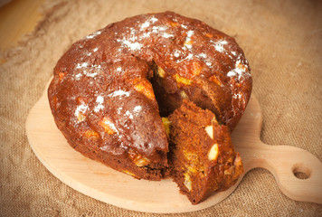 Homemade cocoa cake with fruits in paper on wooden board
