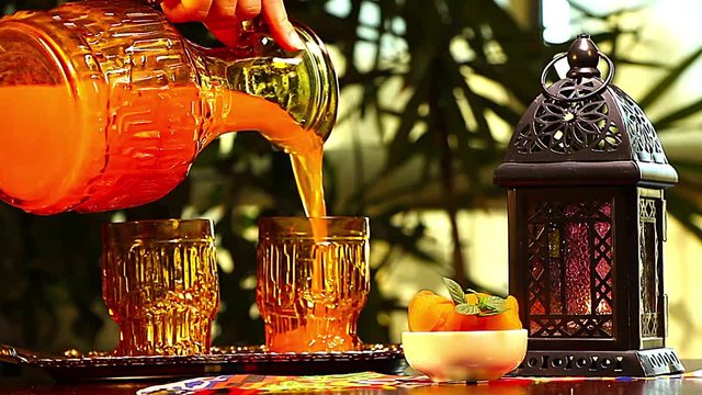 Woman pouring Qamar El Din (Apricot Juice) into a glass , ready for happy breakfast in Ramadan
