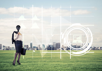 Camera headed woman standing on green grass against modern citys