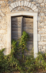 Fototapeta na wymiar very old doors in ancient greek stone building overgrown by ivy