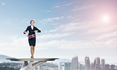 Attractive businesswoman on metal tray playing drums against cityscape background