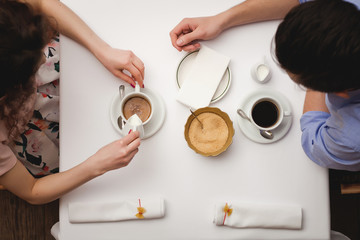 Young enamored couple sitting at a table in a cafe and drinks co