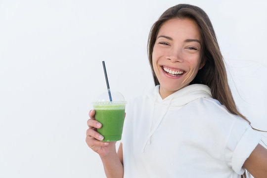 Happy Asian woman drinking healthy green spinach smoothie cup detox for weight loss diet. Young smiling fitness sporty girl with vegetable juice drink from juicing bar health trend, white background.