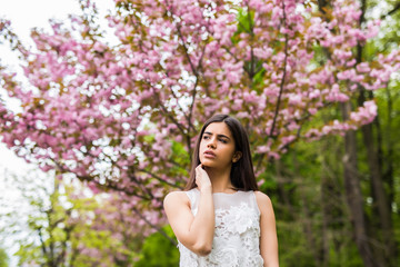 Fototapeta premium Spring beauty girl outdoors near Bbooming sakura tree.