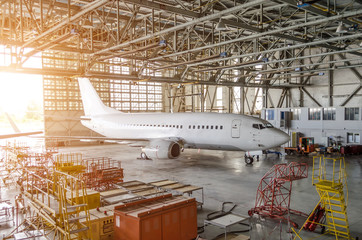 Airliner aircraft in a hangar with an open gate to the service. - obrazy, fototapety, plakaty