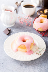 Delicious donuts with pink glaze on light gray background. Selective focus. Copy space.