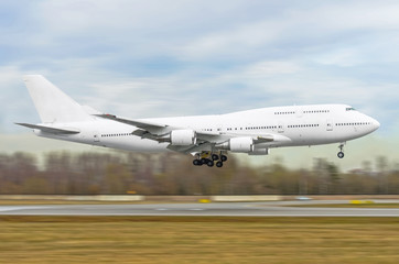 Big white passenger airplane is landing to runway of airport.