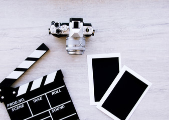 Movie production clapper board, vintage camera with photo cards with copy space against wooden...