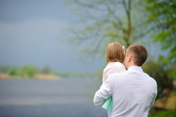 Fototapeta premium father with the little daughter walk on the river bank, look in a distance and reflect