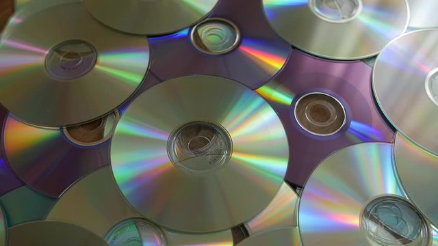 Optical Discs falling onto big pile of DVDs or CDs. Slow motion.