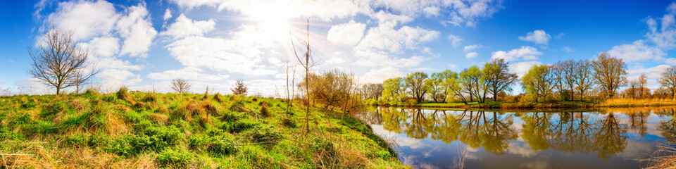 Panorama einer Landschaft mit Sonne, Fluss und Wiesen