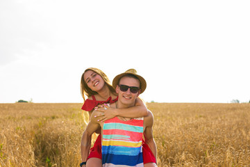 Happy Couple Having Fun Outdoors on wheat field. Laughing Joyful Family together. Freedom Concept. Piggyback