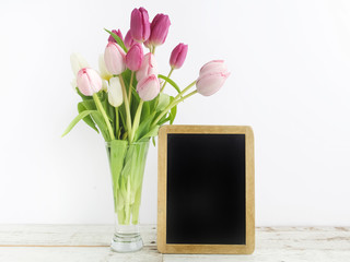 Tulip with blank picture frame on white wooden table