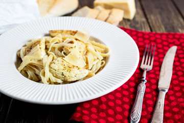 Hearty and delicious dinner, Italian spaghetti with fried chicken, cheese, spices and fresh baguette on a dark wooden background 