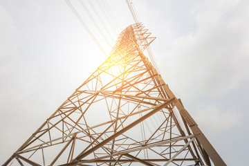 High voltage post against, electricity transmission pylon silhouetted and sunlight of sunset.
