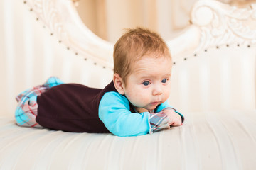 Fototapeta premium Adorable baby boy with red hair and blue eyes. Newborn child lyling in couch.
