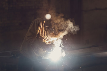 worker welding metal with sparks at factory.