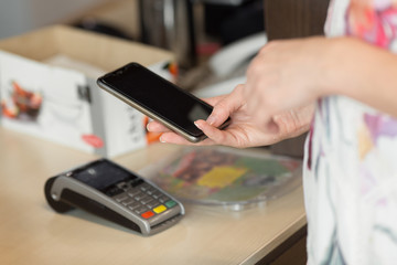 Woman paying bill through smartphone using nfc technology in cafe