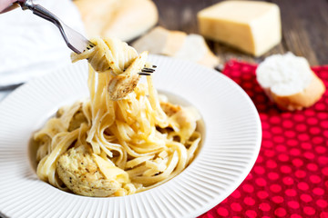Hearty and delicious dinner, Italian spaghetti with fried chicken, cheese, spices and fresh baguette on a dark wooden background 