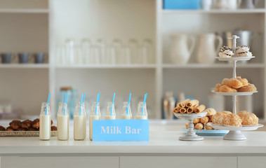Bottles, desserts and card with text MILK BAR on table