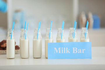 Bottles and card with text MILK BAR on table