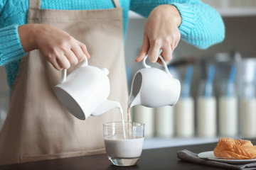 Woman hands pouring milk in cup, closeup