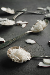 Composition with coconut shavings and vintage spoons on gray background