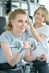 Young woman with her teenage daughter in a gym with dumbbells