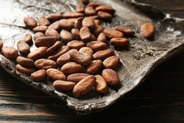 Tray with aromatic cocoa beans on wooden table