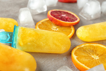 Tasty popsicles with ice cubes and citrus slices, closeup