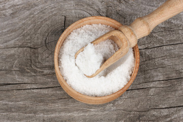 salt on wood plate on old wooden table. Top view