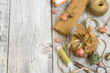 
 Creativity Packing gifts in vintage style with the use of natural materials.  Paper, decorative tape, dried flowers, threads and scissors on a gray wooden background.
