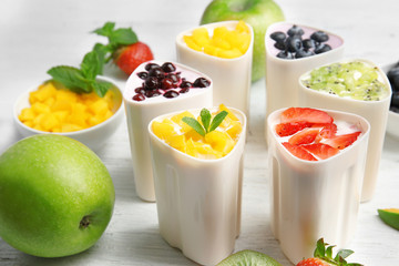 Bowls from automatic yogurt maker with fruits on wooden background