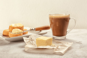 Composition with tasty butter coffee and toasts on textured table