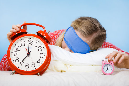 Sleeping woman wearing pajamas holding clock