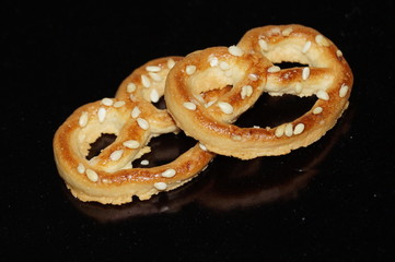 Sweet pretzel with sesame seeds isolated on black background