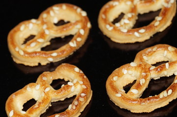 Sweet pretzel with sesame seeds isolated on black background