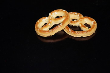Sweet pretzel with sesame seeds isolated on black background