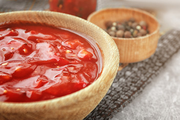 Bowl with tasty chili sauce on table, closeup