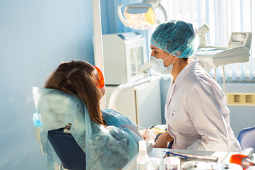 Woman dentist in the medical dental office. She is heals patient