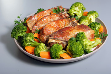 Pork ribs baked in oven with broccoli on plate.