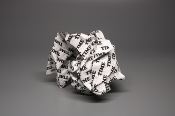 A crumpled paper with the word "time" written all over it on a grey background.